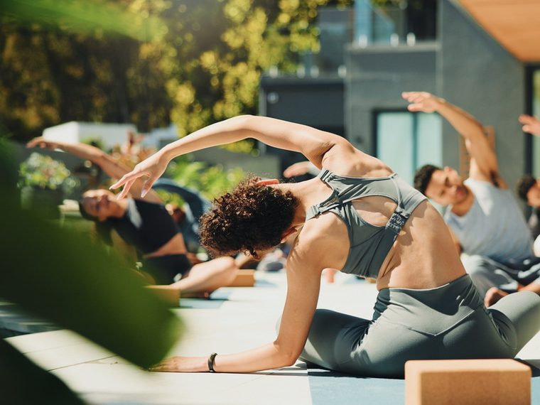 An outdoor yoga class stretching on mats in the sun