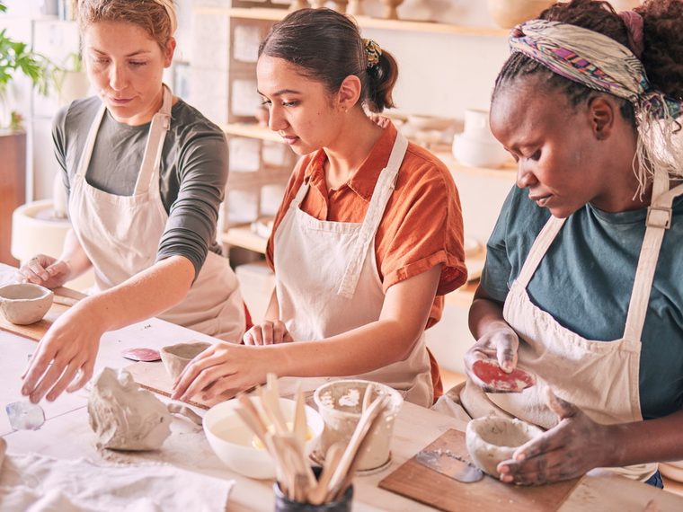 Three friends making pottery together in a studio