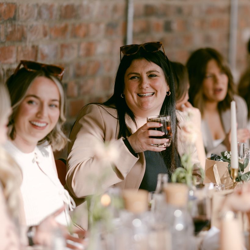 Friends laughing together over a shared table at a community event