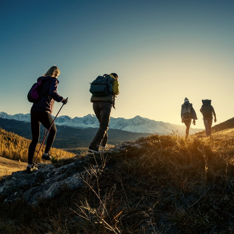 A walking group heading up a hillside at sunset