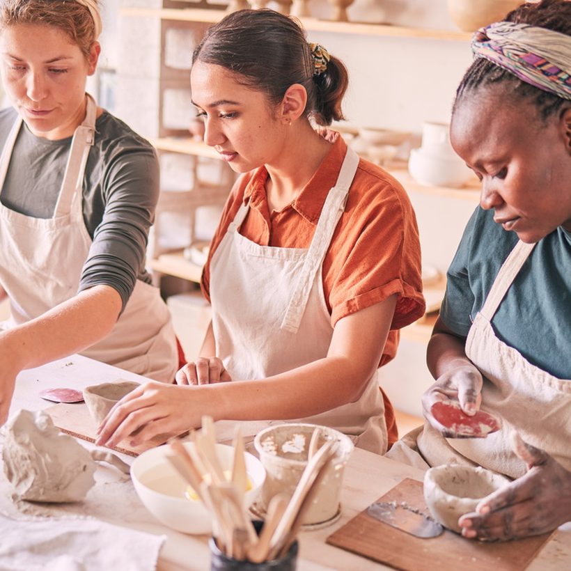 Three friends making pottery together in a studio