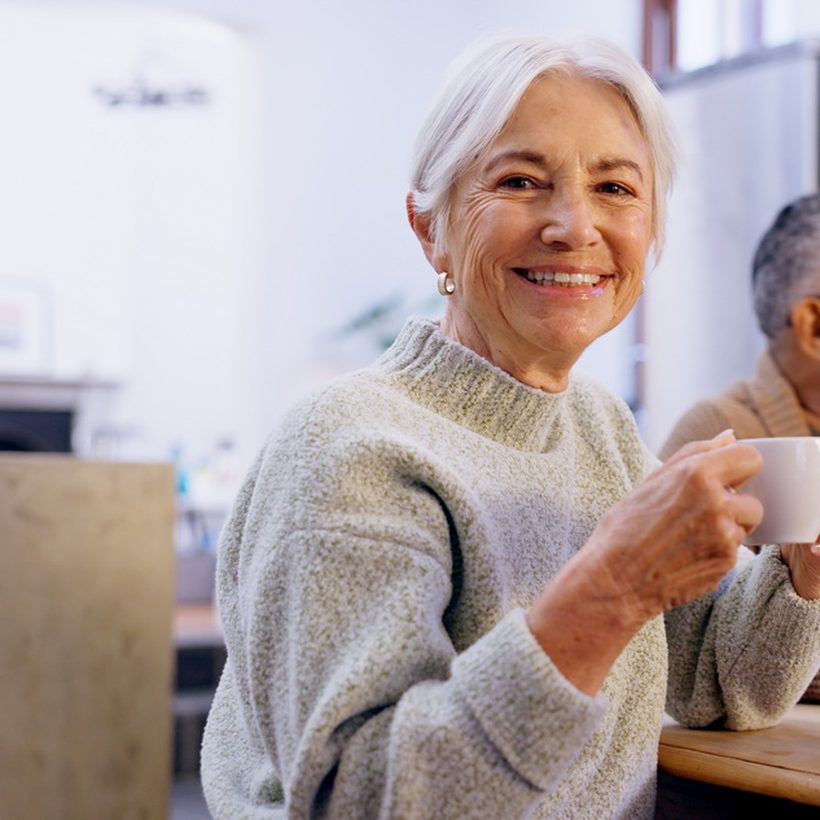 A smiling older woman with a cup of tea among friends