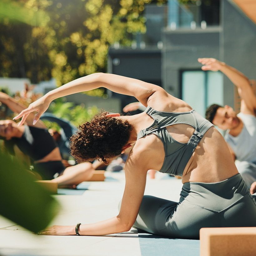 An outdoor yoga class stretching on mats in the sun